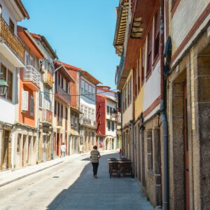 Sunny day view of a charming, historic street in Guimarães, Portugal with colorful architecture.