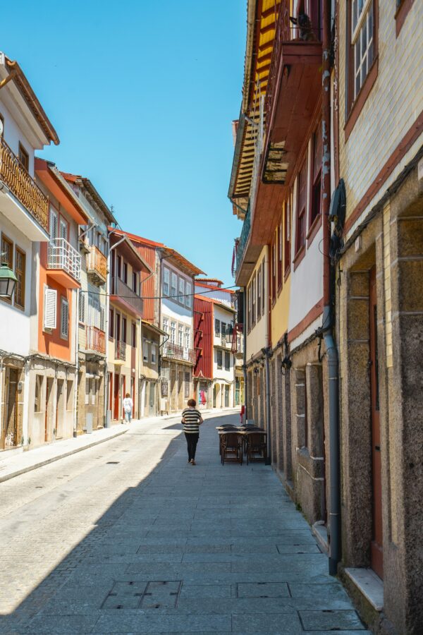 Sunny day view of a charming, historic street in Guimarães, Portugal with colorful architecture.